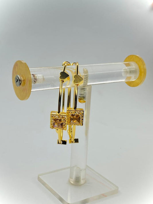 Gold earrings on a clear stand with a white background